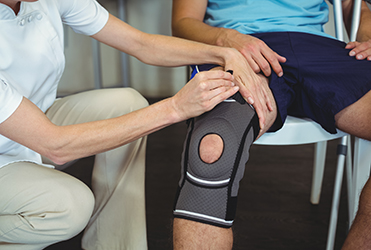Physiotherapist examining patients knee in clinic by Miller Orthopedic Specialists