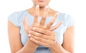 A woman holds her right hand as she is experiencing pain in her fingers and hand.