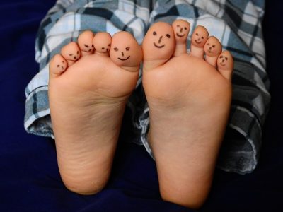 A bare-footed person who has smiley faces that were drawn on all their toes.