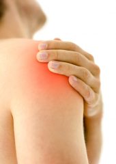 A person holds their shoulder in pain. They might have a torn rotator cuff.
